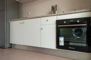eine Küche mit weißen Schränken und einer Mikrowelle in der Unterkunft Brand New Chic Appt in Mindelo at Great Rates in Mindelo