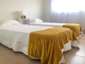 2 Betten mit gelben Decken auf einem Zimmer in der Unterkunft Brand New Chic Appt in Mindelo at Great Rates in Mindelo + 4 Fotos