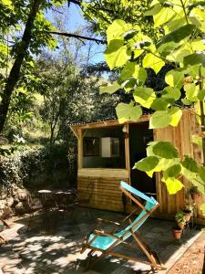 uma cabana com uma mesa e cadeiras à sua frente em LE PETIT REFUGE DU VAL D’EMERAUDE em Soudorgues