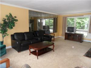 a living room with a black couch and a tv at Pinebrook - Three Bedroom House in Lake George