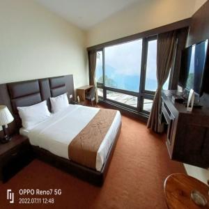 een hotelkamer met een bed en een groot raam bij Istana Resort & Spa in Darjeeling
