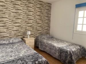 プラヤ・デル・クーラにあるDemelza Beachのレンガの壁、ベッド2台が備わるベッドルーム1室が備わります。