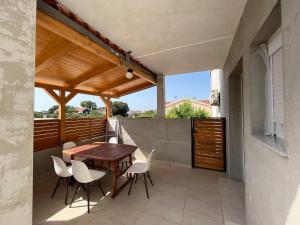 a patio with a wooden table and white chairs at Apartmani Mia in Drage