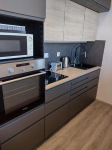 a kitchen with a stove and a microwave at Kilátó Apartman in Tapolca