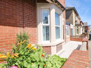 a brick house with a window and some flowers at Lobster Pot Retreat in Newbiggin-by-the-Sea