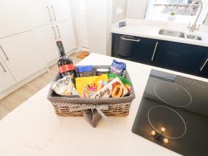 a basket of food and wine on a counter next to a laptop at Lobster Pot Retreat in Newbiggin-by-the-Sea
