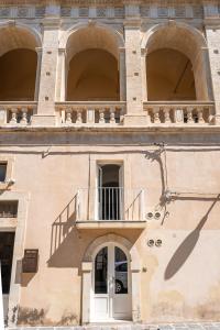 un bâtiment avec trois arches et un balcon dans l'établissement I 5 Archi di Via Ducezio, à Noto