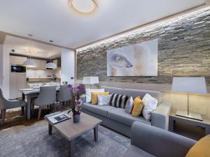 a living room with a couch and a stone wall at Appartement moderne à Courchevel Village, près des commerces et pistes, parking et salle de fitness inclus - FR-1-562-38 in Courchevel