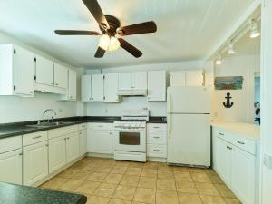 cocina con armarios blancos y ventilador de techo en 7 Beachside inn, en Hampton