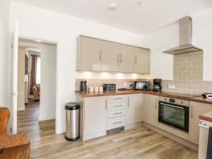 a kitchen with white cabinets and a stove top oven at Lily Cottage in Downham Market