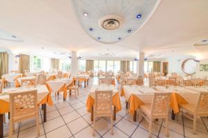 una sala da pranzo con tavoli e sedie bianchi di Hotel Felix Terme a Ischia