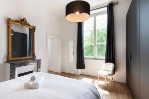 a bedroom with a bed and a mirror and a fireplace at L'élégant de Stanislas in Nancy