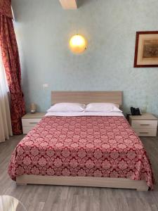 a bedroom with a bed with a red comforter at Hotel Giulietta e Romeo in Casal Palocco