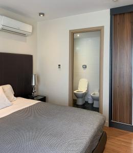 a bedroom with a bed and a bathroom with a toilet at Regency Way Montevideo Hotel in Montevideo