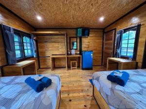a room with two beds and a desk in a cabin at Phu Naphat Resort in Tha Kradan