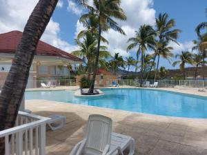 a swimming pool with chairs and palm trees at Paradise01 in Les Terres Basses