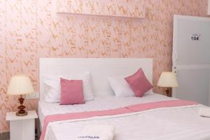 a bedroom with a bed with pink and white pillows at Bohemian Villa - Negombo in Negombo