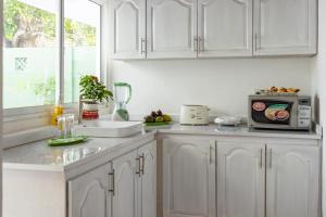 a kitchen with white cabinets and a microwave at Bohemian Villa - Negombo in Negombo