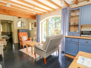 una cocina con armarios azules, una silla y una mesa en The Garden Flat, en Fort William