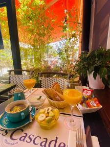 a table with a plate of food and glasses of orange juice at Les Cascades - Hôtel de Charme in Honfleur