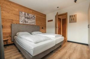 a bedroom with two white beds and a wooden wall at Apartment Typ D im Alpin Resort Mo in Gargellen