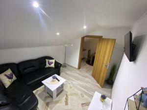 - un salon avec un canapé noir et une table dans l'établissement Apartman FILIP, à Udbina