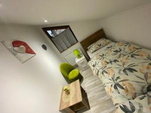 um pequeno quarto com uma cama e uma cadeira verde em Apartman FILIP em Udbina