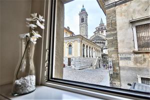 a window with a view of a building with a clock tower at ASTRA-Modern Loft Cathedral View in Bergamo