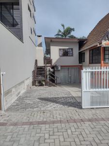 a house with a white fence and a brick driveway at APARTAMENTO MARISCAL in Bombinhas
