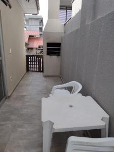 a white table and chairs sitting on a balcony at APARTAMENTO MARISCAL in Bombinhas