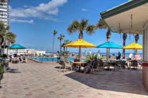 people sitting at tables under umbrellas near a pool at Daytona Beach Resort Unit #302 in Daytona Beach