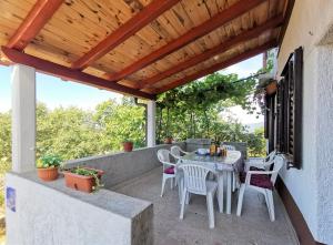 a patio with a table and chairs under a wooden roof at Apartment Dina in Cres