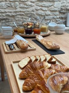 a table with bread and croissants and pastries on it at Chambre d'hôtes Hôte des Portes Île de Ré in Les Portes