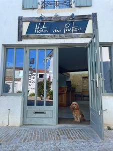 a dog sitting in the doorway of a house at Chambre d'hôtes Hôte des Portes Île de Ré in Les Portes