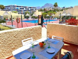 une table avec des assiettes et des verres à vin et une vue sur une piscine dans l'établissement El cortijo, pool view, à Playa de las Americas
