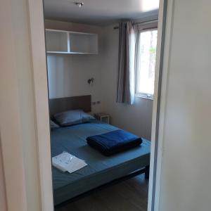 a small bedroom with a bed and a window at Camping ONLYCAMP LES PINS in Nançay