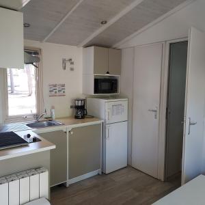 a kitchen with a white refrigerator and a sink at Camping ONLYCAMP LES PINS in Nançay