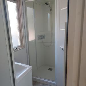 uma casa de banho com um chuveiro e uma porta de vidro em Camping ONLYCAMP LES PINS em Nançay