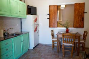 cocina con armarios verdes, mesa y nevera en Kantounia Stonehouse en Vavkerí