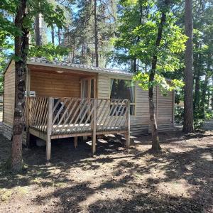 a wooden cabin with two benches in the woods at Camping ONLYCAMP LES PINS in Nançay