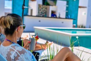 une femme assise sur une chaise en train de boire un verre dans l'établissement The Cove Boutique Hotel Adults Only, à Puerto Peñasco