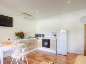 a white kitchen with a table and a refrigerator at Appartement tranquille en bas de villa in Afa +3 photos