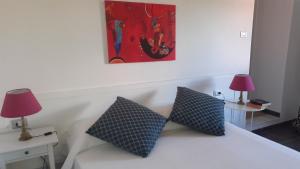un letto bianco con due cuscini e due lampade di Casa Chiocconi a La Spezia