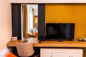 um quarto com uma secretária e uma televisão de ecrã plano em Hotel River em Luduş