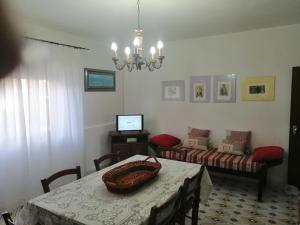 uma sala de estar com uma mesa e uma televisão em MISTRAL HOLIDAY HOME em Putzu Idu