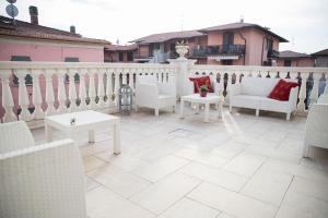 un patio con sedie bianche e tavoli sul balcone di Villa del Tempo a Desenzano del Garda