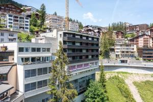 an apartment building in a city with trees at Cristallo Arosa Hotel in Arosa