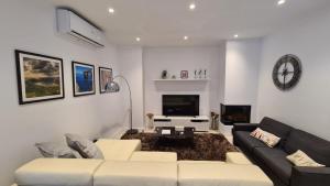 a living room with a couch and a tv at Modern and bright 3 bedroom villa with pool. in San Ġwann