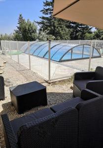 a fence with chairs and a table in front of a pool at GiTE ATYPIQUE AVEC PISCINE COUVERTE en saison in St Apollinaire De Rias