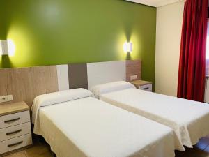 2 camas en una habitación con paredes verdes en Hostal Labranza en Fuenmayor